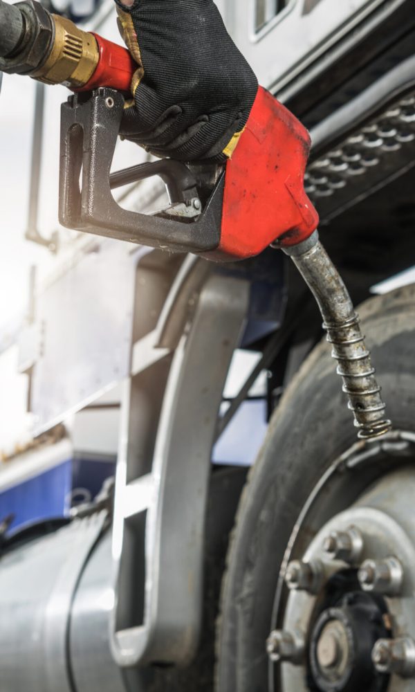 Aged Semi Truck Driver About to Refuel His Tractor Truck Holding Diesel Pump Nozzle in His Hand. Heavy Duty Transportation and Fuel Shortage Concept.